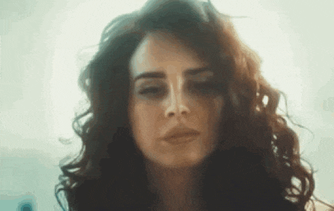 a close up of a woman 's face with curly hair looking down .