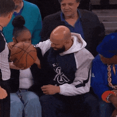 a man holding a basketball while wearing a jacket with k on it