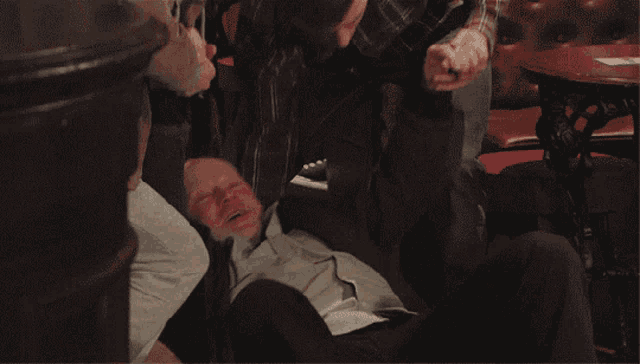 a bald man with his arms in the air is surrounded by people