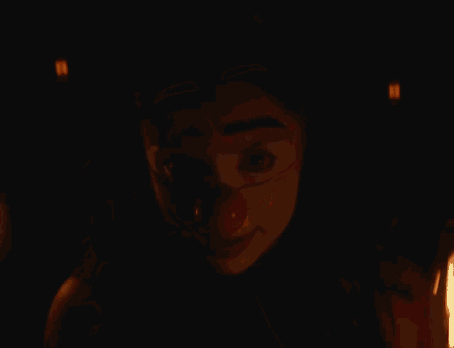 a woman wearing a clown mask with a red nose smiles