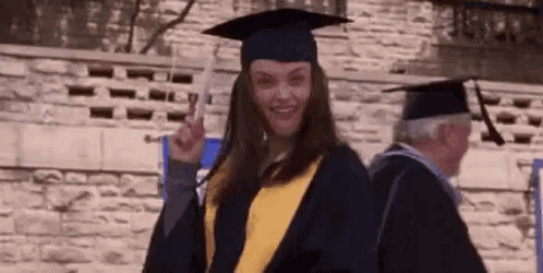 a woman in a graduation cap and gown is giving the middle finger while standing next to a man .