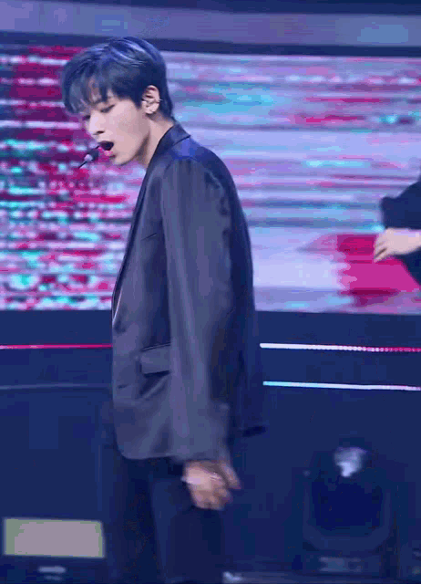 a man in a suit is dancing on a stage with a microphone in his mouth