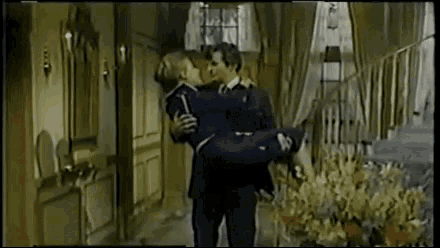 a man in a suit is carrying a woman in his arms in a room .