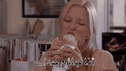 a woman is eating a hamburger in a room with arabic writing .
