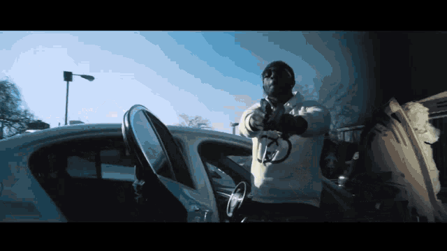 a man in a white hoodie is pointing a gun