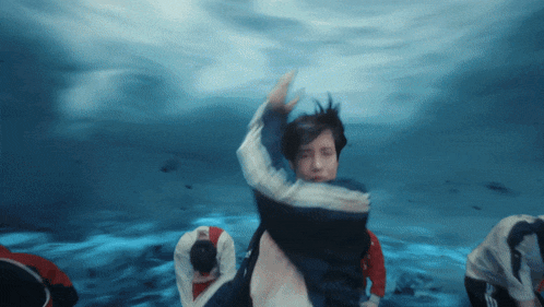 a group of people are dancing underwater in a pool