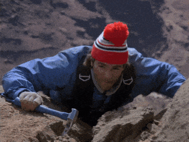 a man wearing a red white and blue hat holds a hammer in his hand