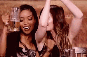 two women are holding beer mugs in their hands and dancing .
