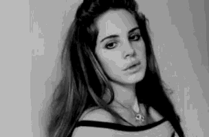 a black and white photo of a woman wearing a necklace .