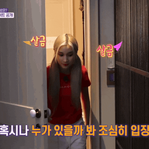 a woman in a red shirt stands in a doorway