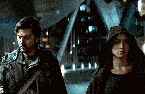 a man and a woman are walking in a dark room