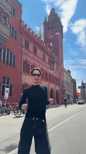 a man wearing sunglasses stands in front of a red building with the letter b on the front