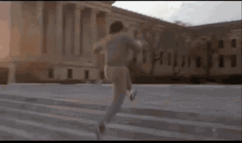 a man is running up a set of stairs in front of a building .