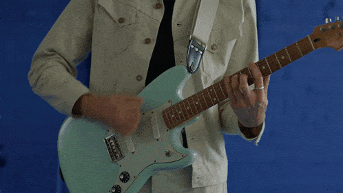 a man playing a guitar with a strap that says ' fender ' on it