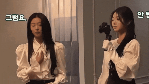 a woman in a white shirt is holding a camera in her right hand
