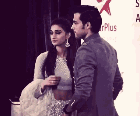 a man and a woman are standing next to each other in front of a sign that says star plus .