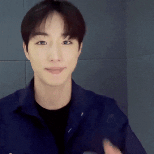 a young man wearing a blue jacket and black shirt is smiling