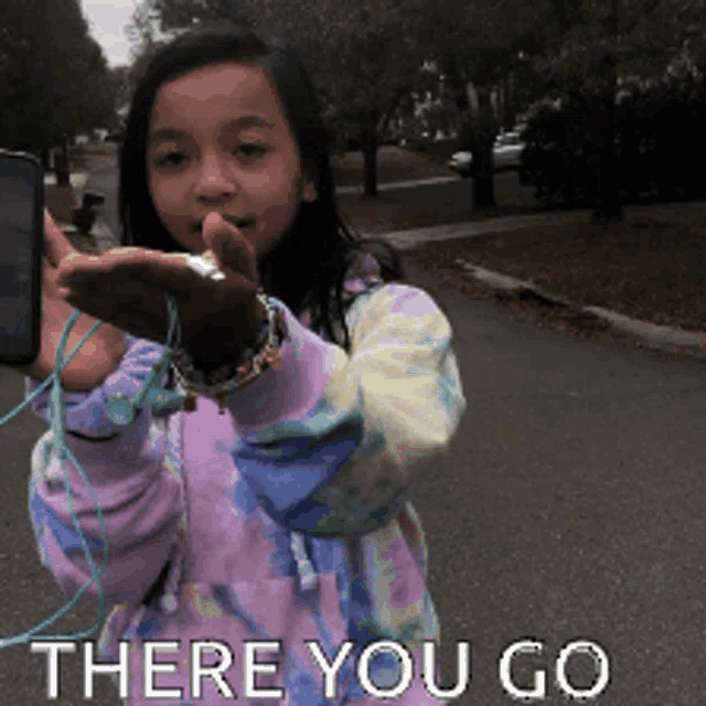 a young girl holding a cell phone with the words " there you go " written below her