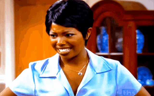 a woman in a blue shirt is smiling in front of a cabinet with the letters tbs on it