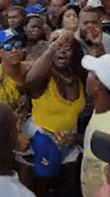 a woman in a yellow shirt is dancing in a crowd