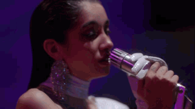 a close up of a woman singing into a microphone with a tattoo on her finger that says z