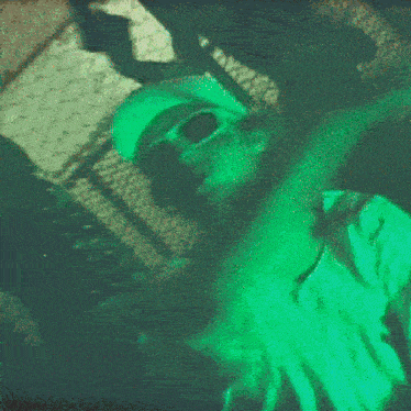 a blurry image of a person wearing sunglasses and a green hat