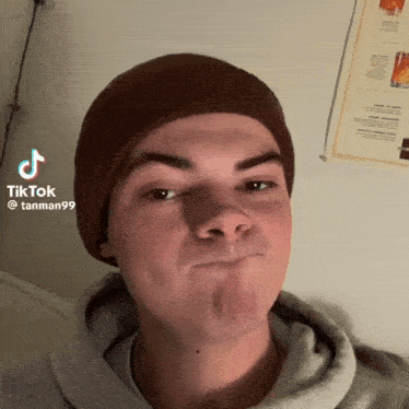 a young man wearing a brown beanie and a tanman99 hoodie