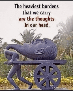 a statue of a man carrying a large head on a cart with a quote about the burdens we carry