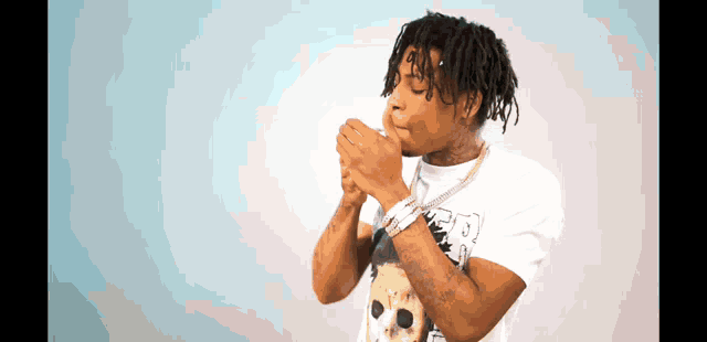 a man with dreadlocks is wearing a white t-shirt with a skull on it