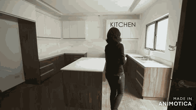 a woman stands in a kitchen with the word kitchen on the wall