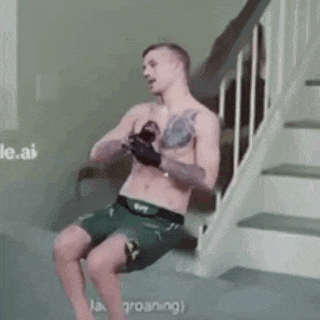 a shirtless man is sitting on a staircase holding a cell phone .