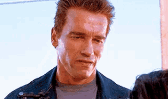 arnold schwarzenegger is wearing a denim jacket and a gray shirt .