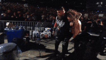 two men are wrestling in front of a crowd and the letters w and n are on the bottom of the screen