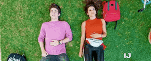 a man and a woman are laying on the grass with a backpack .