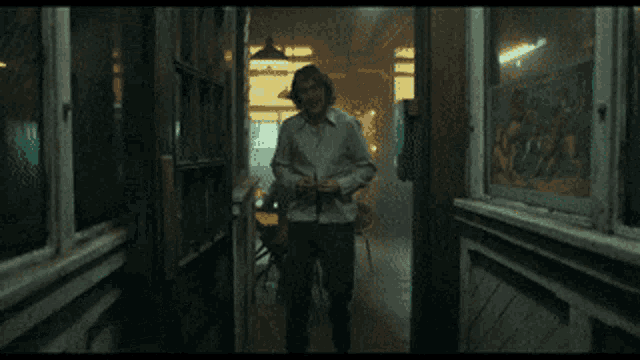a man in a white shirt is laughing in front of a window