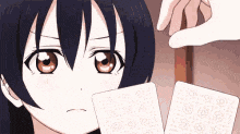 a girl is holding two playing cards in front of her face .