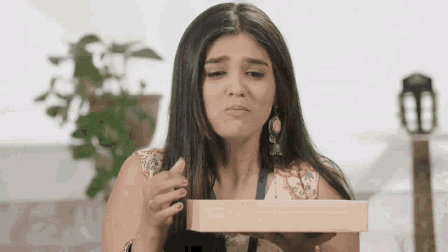 a woman is holding a wooden box in her hand and making a funny face .