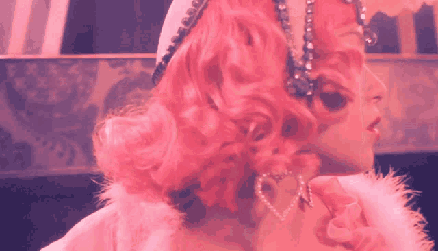 a woman with pink hair and heart shaped earrings looks to the side