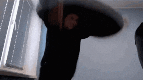 a person is standing in front of a window in a dark room holding a large object .