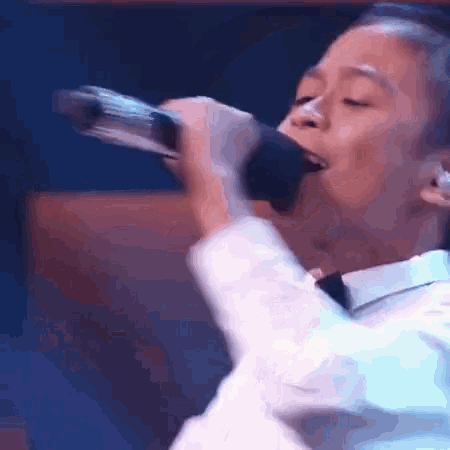 a man in a tuxedo is singing into a microphone on a stage .