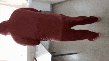 a man in a red hoodie and red pants is standing in front of a table
