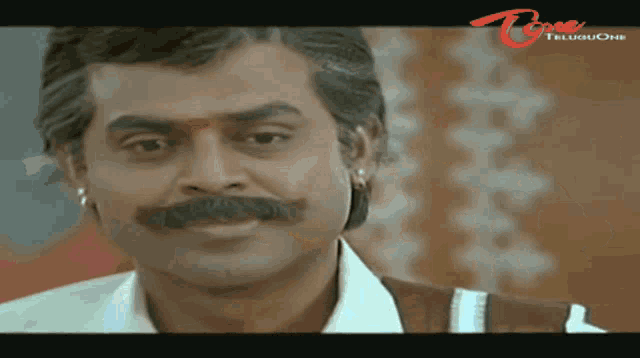 a close up of a man 's face with a telugu one logo in the corner