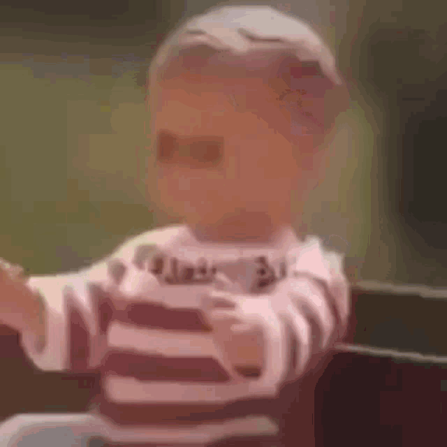 a baby wearing sunglasses and a striped shirt is sitting on a chair .