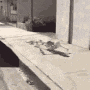 a black and white photo of a person standing on a sidewalk next to a wall .