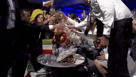 a group of people are sitting around a table toasting with champagne glasses