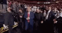 a blurry picture of a man in a suit and tie standing in front of a crowd .