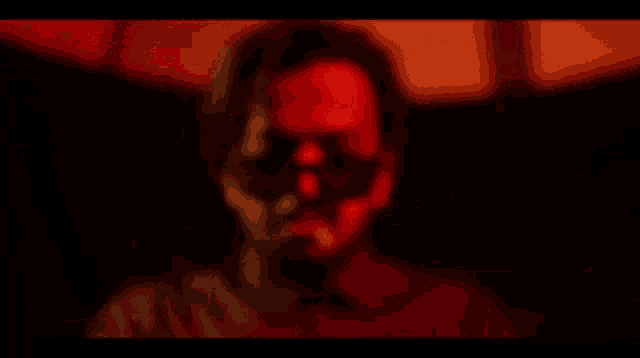 a blurry picture of a man 's face with a red light behind him .