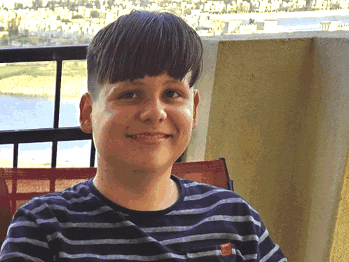 a young boy wearing a striped shirt is smiling and looking at the camera