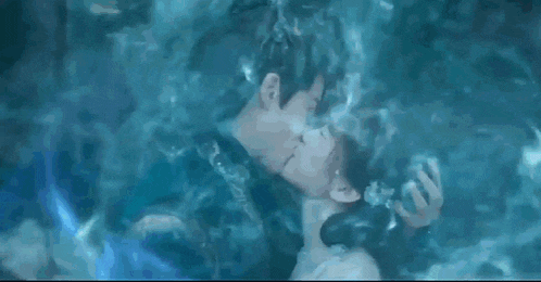 a man and a woman kissing underwater in a pool .