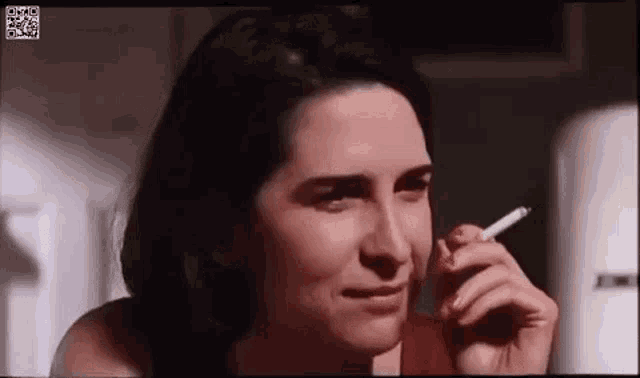 a woman is smoking a cigarette in a dark room and crying .